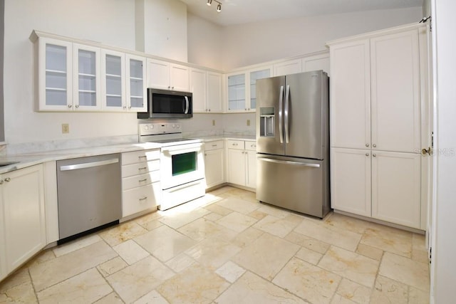 kitchen with high vaulted ceiling, white cabinetry, appliances with stainless steel finishes, glass insert cabinets, and stone tile flooring