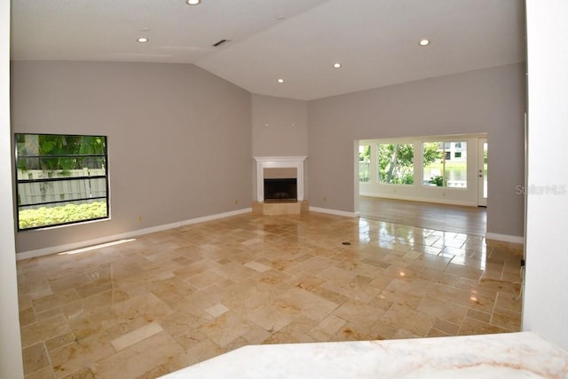 unfurnished living room with baseboards, vaulted ceiling, visible vents, and stone tile flooring