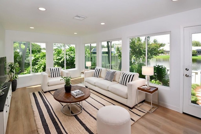 sunroom featuring a water view