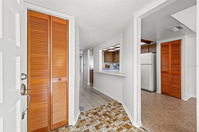 hall featuring a textured ceiling and light hardwood / wood-style floors