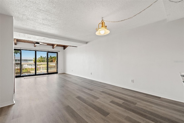 spare room featuring a textured ceiling, dark hardwood / wood-style floors, and beamed ceiling