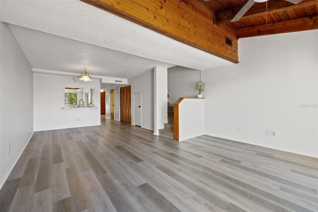 unfurnished living room with wood ceiling, a textured ceiling, hardwood / wood-style floors, and ceiling fan