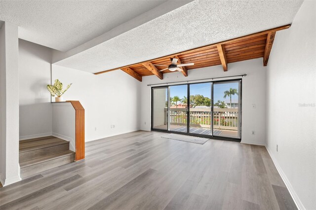 unfurnished room with a textured ceiling, wood-type flooring, wood ceiling, lofted ceiling with beams, and ceiling fan