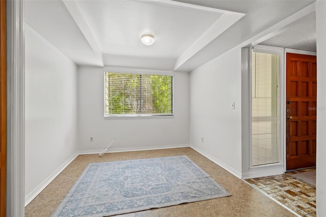 foyer entrance featuring a textured ceiling and baseboards