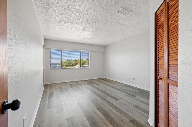 unfurnished room with wood-type flooring and a textured ceiling