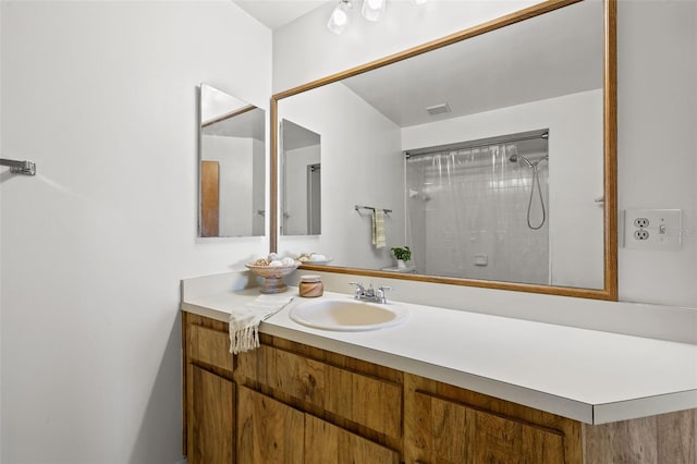 bathroom with visible vents, a shower, and vanity