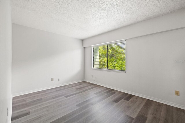 spare room featuring dark hardwood / wood-style flooring and a textured ceiling