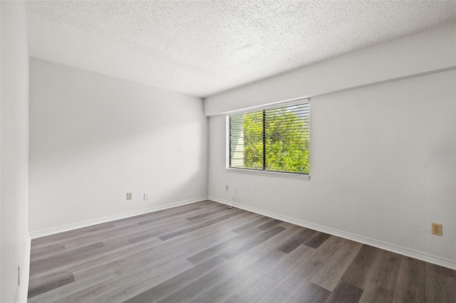 unfurnished room with a textured ceiling, wood finished floors, and baseboards