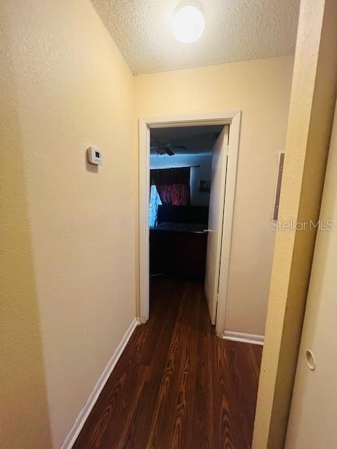 corridor with dark wood-type flooring and a textured ceiling