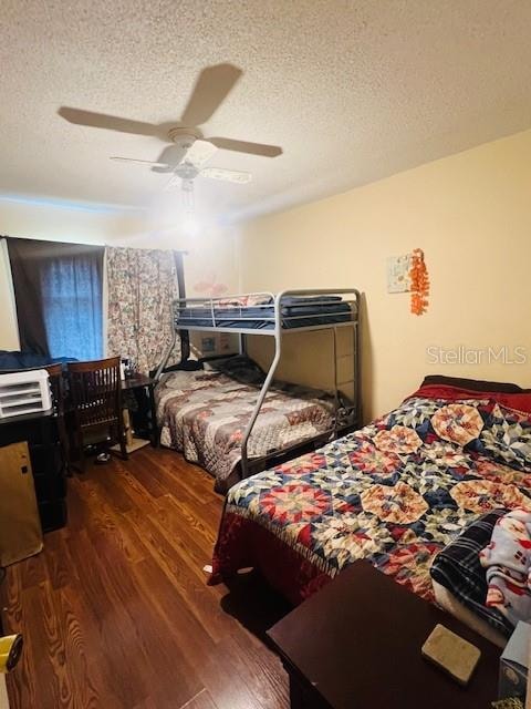 bedroom with ceiling fan, dark hardwood / wood-style flooring, and a textured ceiling