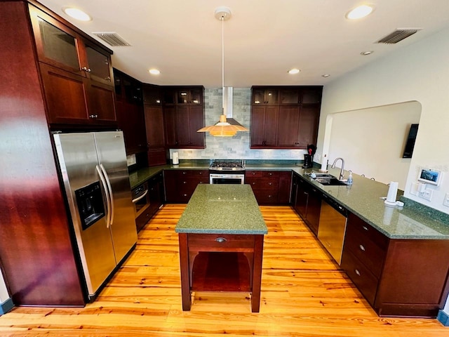 kitchen with stainless steel appliances, kitchen peninsula, light wood-type flooring, and wall chimney range hood