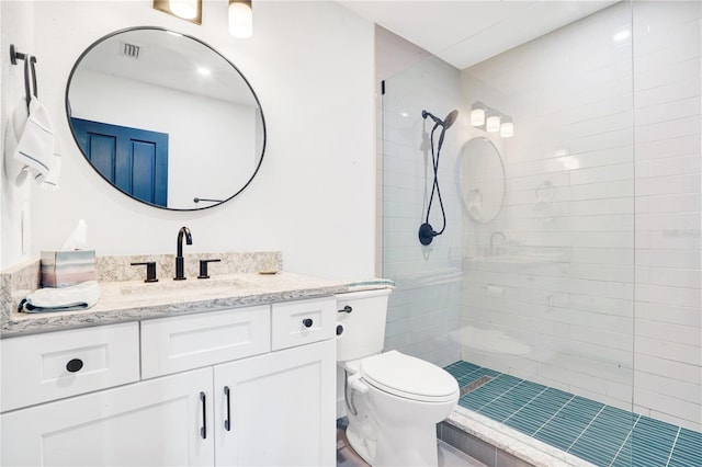 bathroom with toilet, vanity, and tiled shower