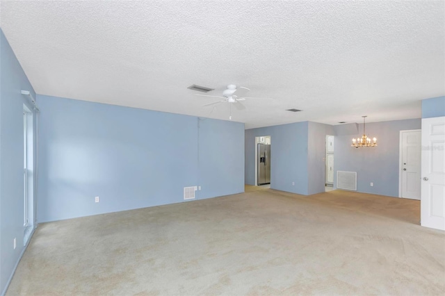 interior space featuring ceiling fan with notable chandelier, light carpet, and a textured ceiling