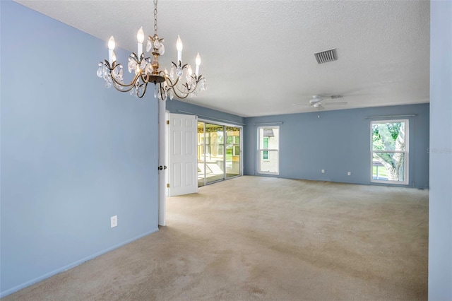 carpeted spare room featuring a textured ceiling and ceiling fan with notable chandelier