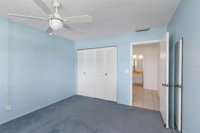 unfurnished bedroom featuring a textured ceiling, ceiling fan, a closet, and carpet floors