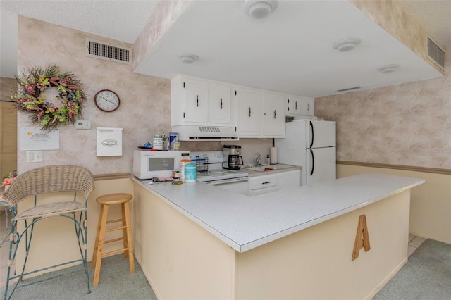 kitchen featuring white appliances, light carpet, kitchen peninsula, ventilation hood, and white cabinets