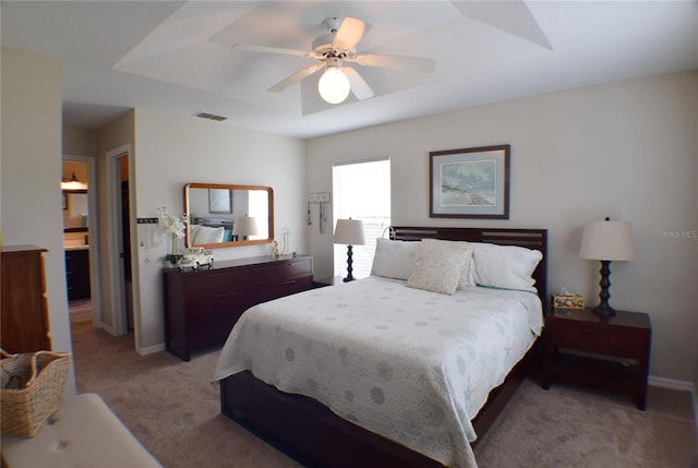 bedroom featuring carpet flooring, connected bathroom, a raised ceiling, and ceiling fan