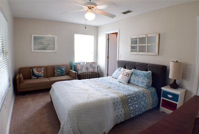 bedroom featuring multiple windows, dark colored carpet, and ceiling fan