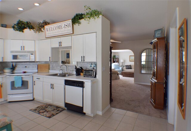 kitchen featuring white cabinetry, white appliances, backsplash, sink, and light colored carpet