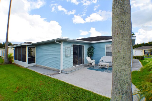 rear view of property featuring a yard, a patio, and a sunroom