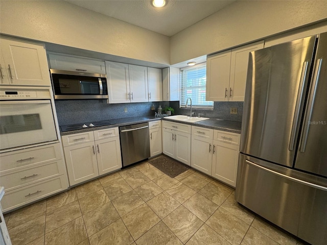 kitchen featuring appliances with stainless steel finishes, white cabinetry, backsplash, and sink