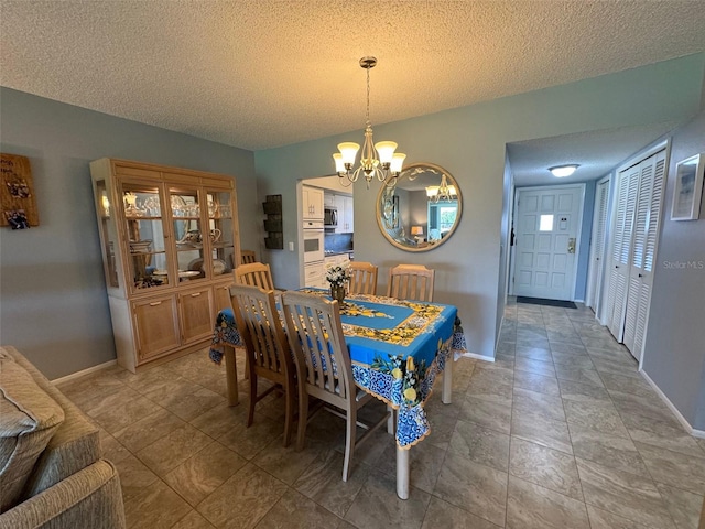 dining area featuring a textured ceiling, an inviting chandelier, and tile patterned floors