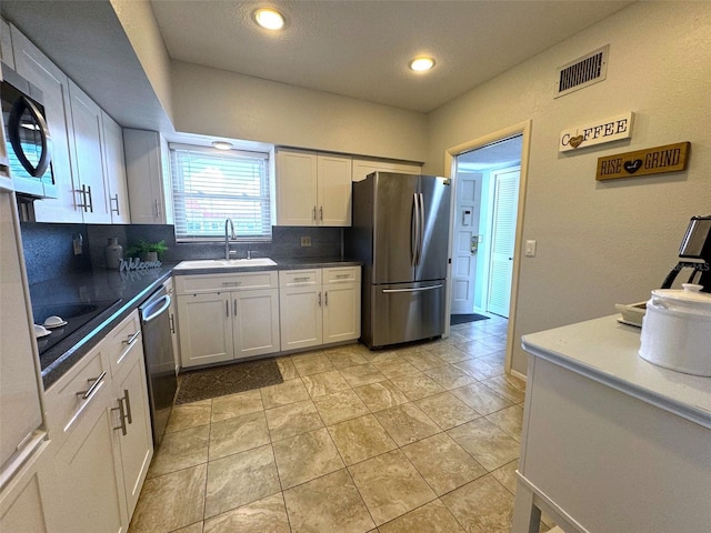 kitchen featuring white cabinets, stainless steel appliances, sink, light tile patterned flooring, and decorative backsplash