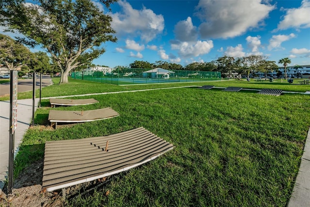 view of home's community with tennis court and a lawn