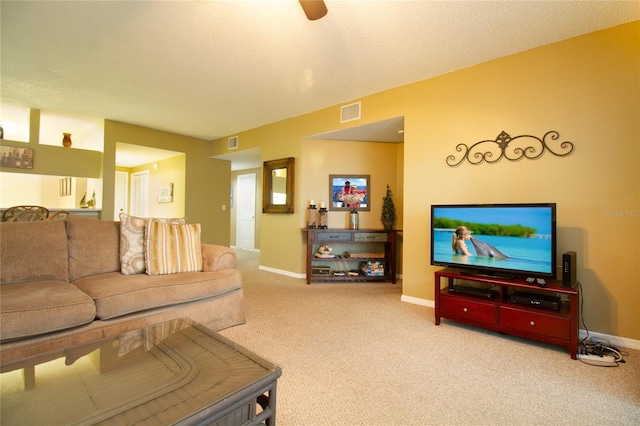 carpeted living room featuring ceiling fan and a textured ceiling