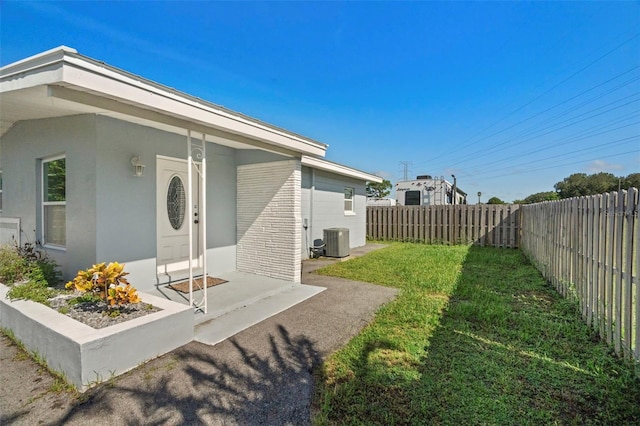 back of property with central AC unit and a lawn