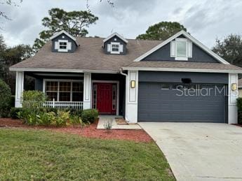 view of front of property with a front yard, covered porch, and a garage