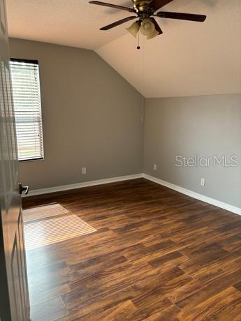 spare room with lofted ceiling, ceiling fan, and dark hardwood / wood-style flooring