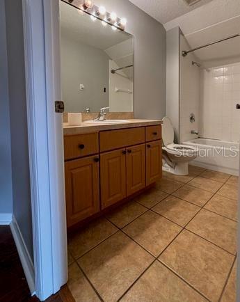 full bathroom featuring tile patterned floors, tiled shower / bath, toilet, and vanity