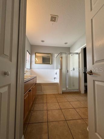 bathroom with tile patterned floors, shower with separate bathtub, and vanity