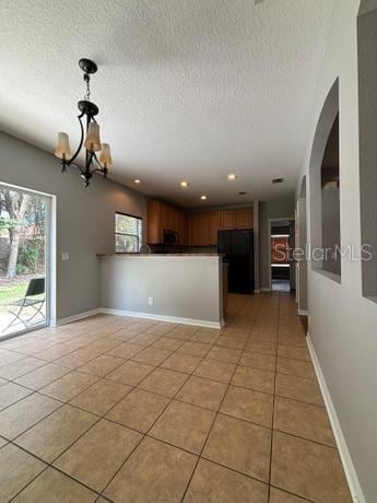 interior space with black fridge, light tile patterned floors, an inviting chandelier, and a textured ceiling