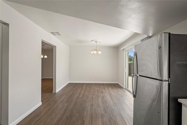 interior space featuring hardwood / wood-style flooring, stainless steel refrigerator, a notable chandelier, and hanging light fixtures