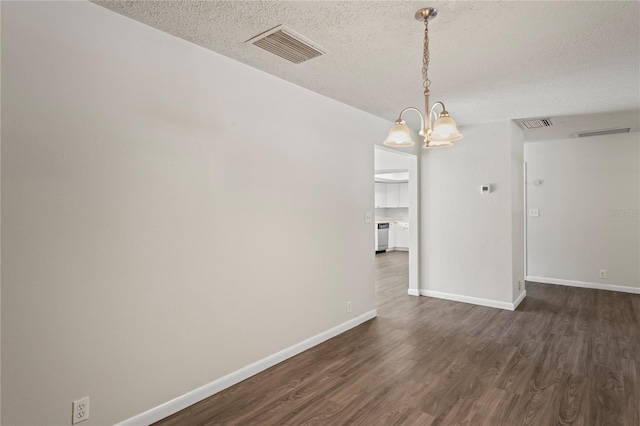 unfurnished room with a textured ceiling, an inviting chandelier, and dark hardwood / wood-style flooring