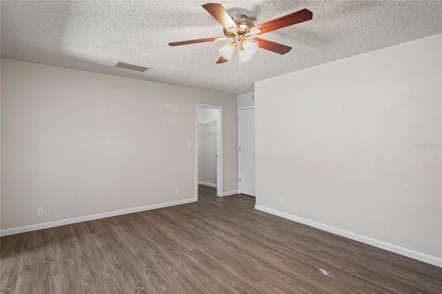 empty room with ceiling fan, dark hardwood / wood-style flooring, and a textured ceiling