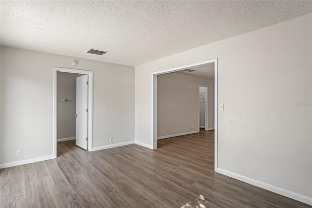 unfurnished room with a textured ceiling and hardwood / wood-style flooring