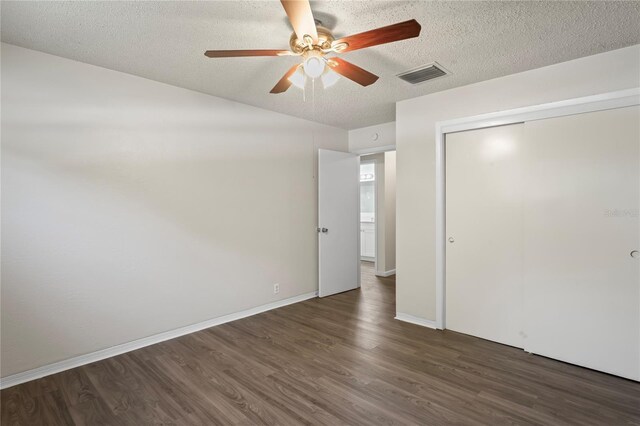 unfurnished bedroom with a closet, dark hardwood / wood-style flooring, ceiling fan, and a textured ceiling