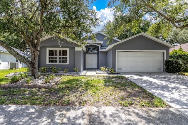 ranch-style house featuring cooling unit, driveway, an attached garage, and stucco siding