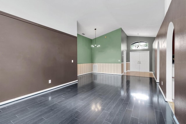 entrance foyer featuring a chandelier, arched walkways, wood finished floors, and visible vents