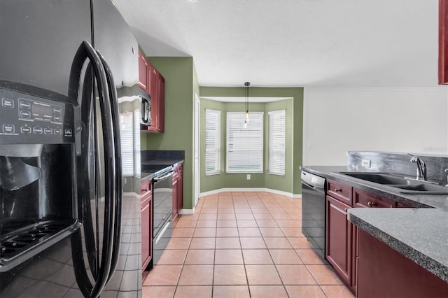 kitchen with reddish brown cabinets, black appliances, dark countertops, and a sink