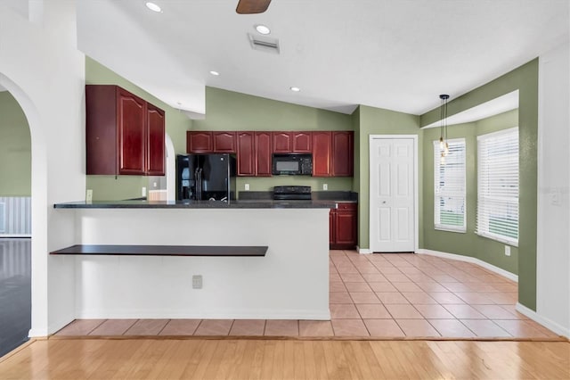 kitchen with reddish brown cabinets, black appliances, dark countertops, and visible vents