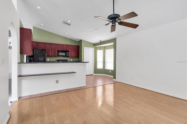 kitchen with light wood-style flooring, a ceiling fan, reddish brown cabinets, black appliances, and dark countertops