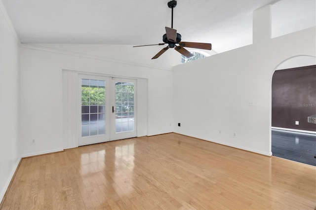 spare room featuring baseboards, arched walkways, wood finished floors, vaulted ceiling, and french doors