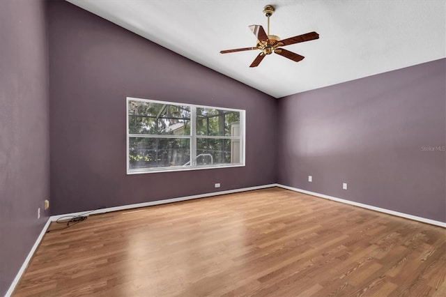 empty room with lofted ceiling, ceiling fan, baseboards, and wood finished floors