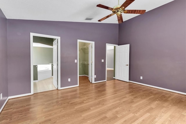 unfurnished bedroom featuring light wood-type flooring, baseboards, a spacious closet, and visible vents