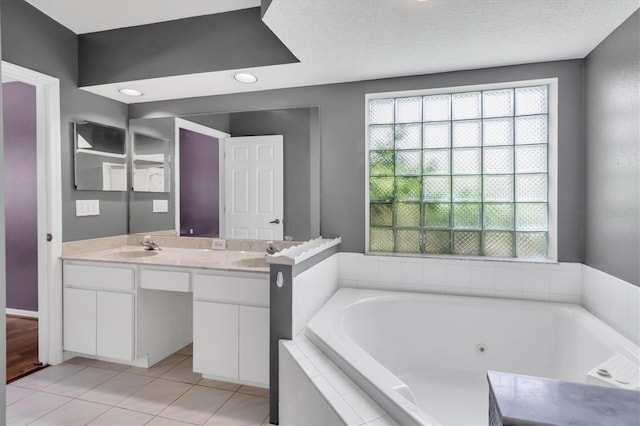 bathroom with double vanity, a sink, a textured ceiling, tile patterned flooring, and a whirlpool tub