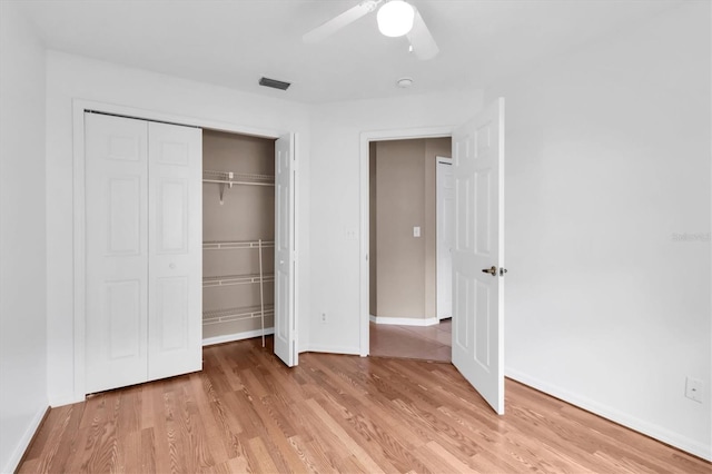 unfurnished bedroom featuring ceiling fan, light wood-style flooring, visible vents, baseboards, and a closet